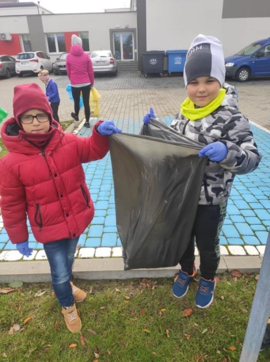 Dzieci wrzucają odpady do worka